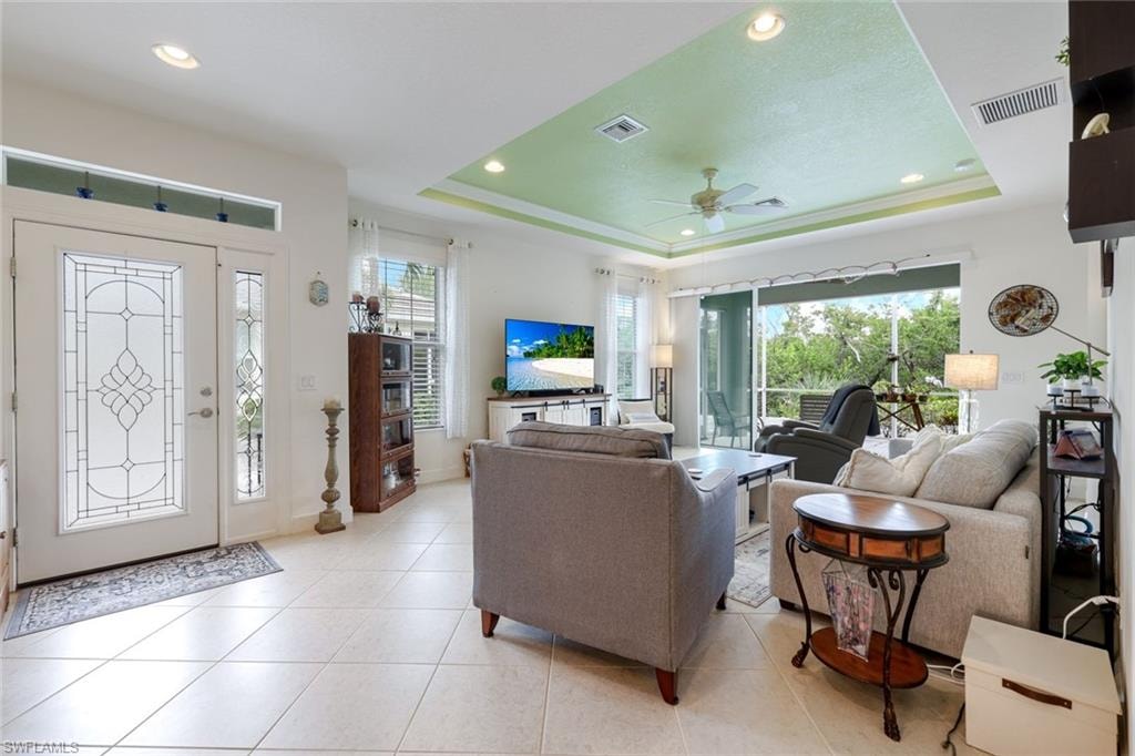 Living room featuring a tray ceiling, recessed lighting, light tile patterned floors, and ceiling fan