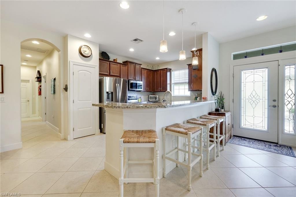 Kitchen featuring light stone countertops, a tray ceiling, decorative light fixtures, stainless steel appliances, and a chandelier