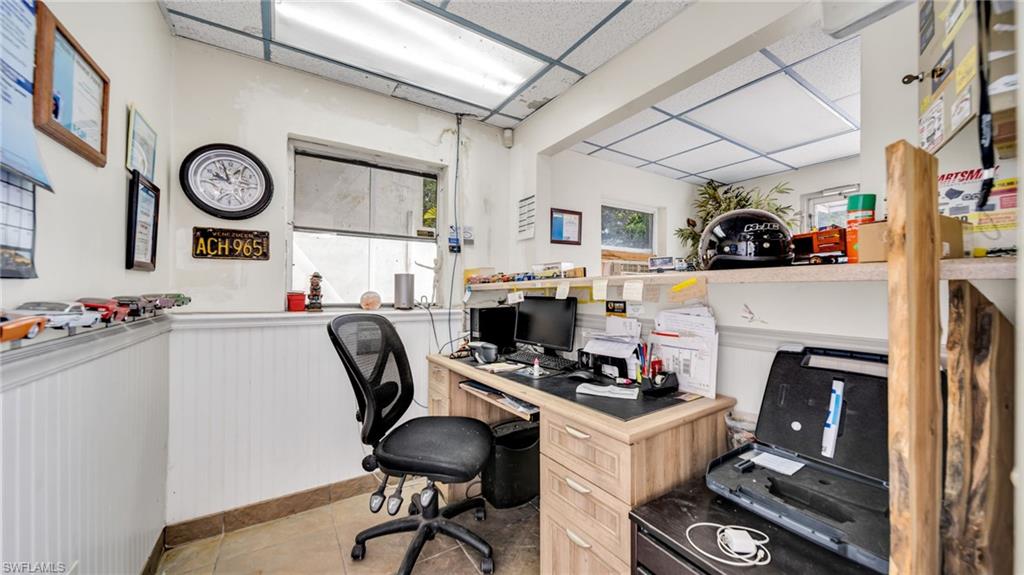 Office area with a paneled ceiling, light tile patterned floors, and wainscoting