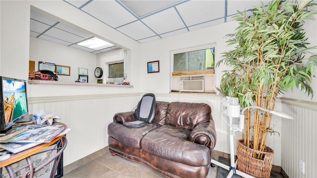 Sitting room with a paneled ceiling, a wainscoted wall, tile patterned flooring, and cooling unit