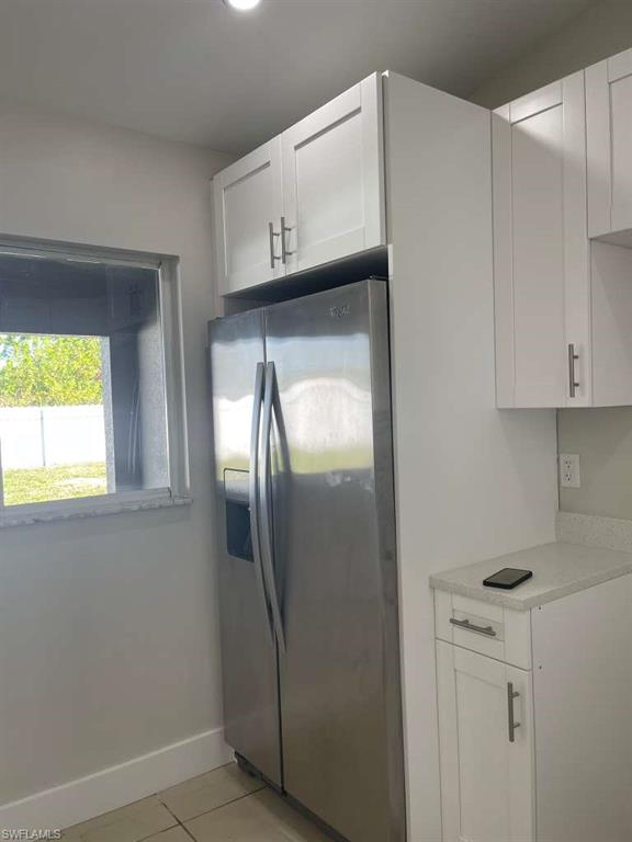 Kitchen featuring white cabinetry, stainless steel fridge with ice dispenser, and light tile patterned flooring