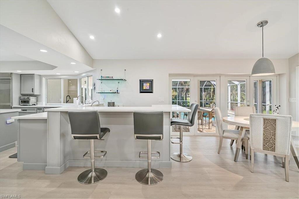 Kitchen with recessed lighting, lofted ceiling, decorative light fixtures, a kitchen breakfast bar, and gray cabinetry