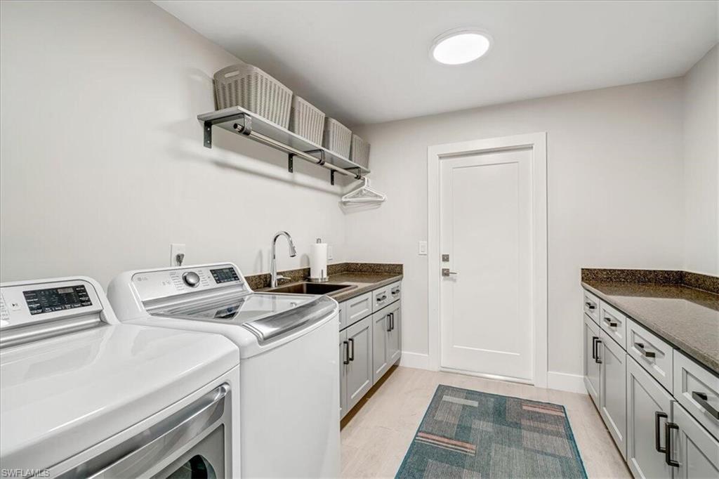 Laundry area with cabinet space, washing machine and clothes dryer, and light wood-type flooring
