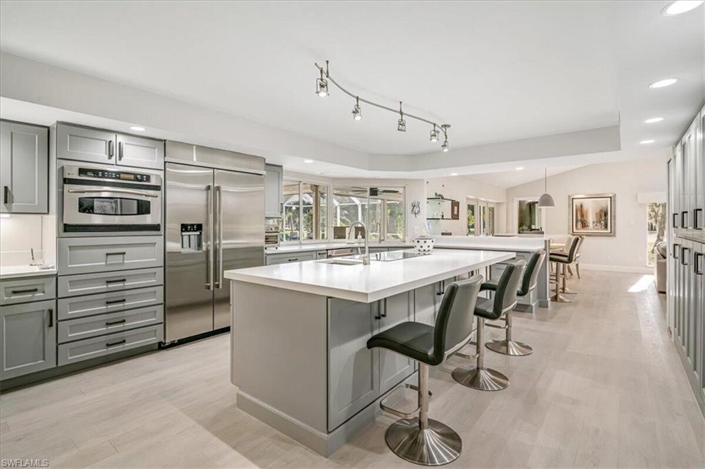 Kitchen featuring gray cabinets, recessed lighting, a breakfast bar, appliances with stainless steel finishes, and light wood-style flooring