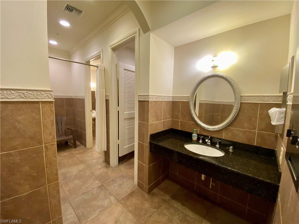 Full bath featuring tile walls, visible vents, a sink, and a wainscoted wall