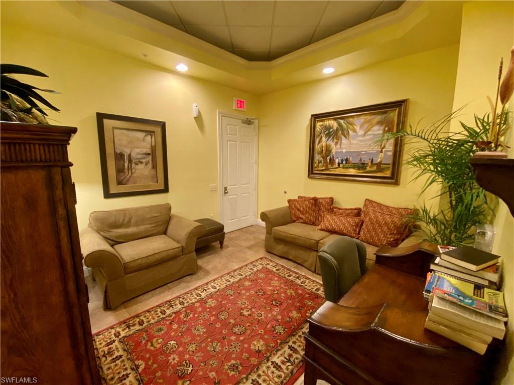 Tiled living area with a tray ceiling, ornamental molding, and recessed lighting