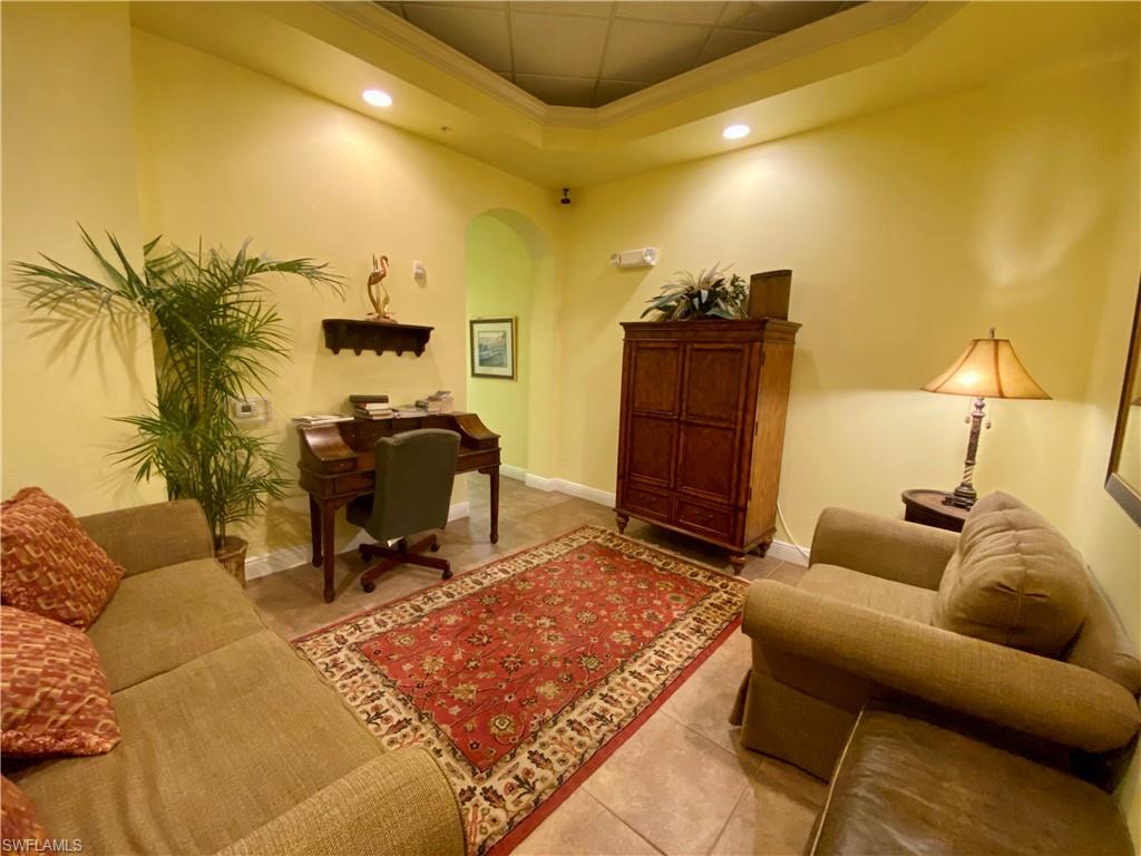 Home office featuring a raised ceiling, tile patterned flooring, baseboards, arched walkways, and recessed lighting