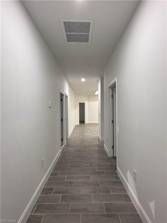 Corridor with baseboards and wood finish floors