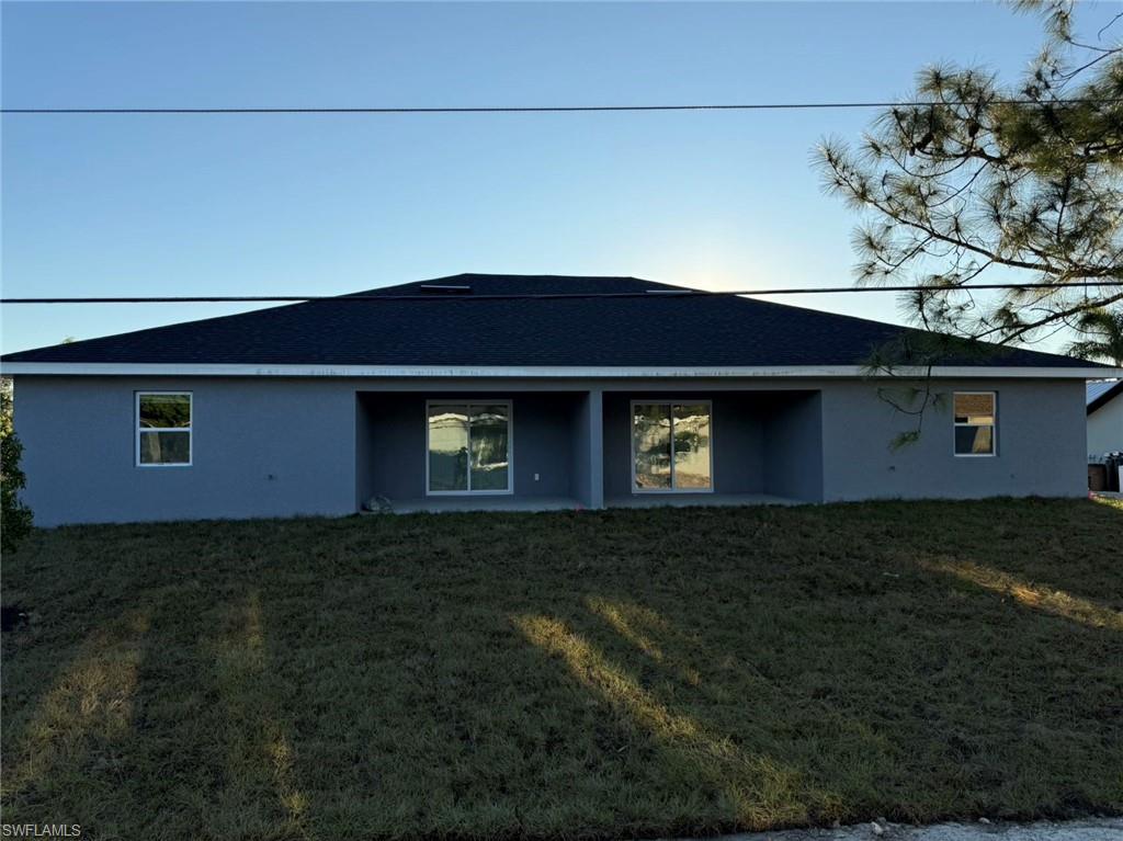 Back of property featuring stucco siding and a lawn