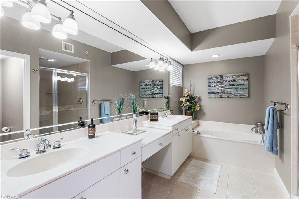The primary spa-inspired bathroom is beautifully appointed with a separate walk-in shower and a tranquil soaking tub, creating a serene, resort-like retreat. Tray ceilings add architectural elegance and height, enhancing the sense of openness and luxury throughout this private sanctuary.