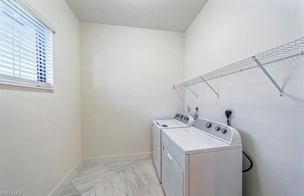 Laundry area featuring light marble finish floors and washer and dryer