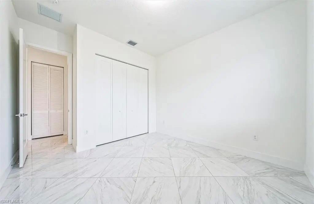 Unfurnished bedroom with a closet and light marble finish floors