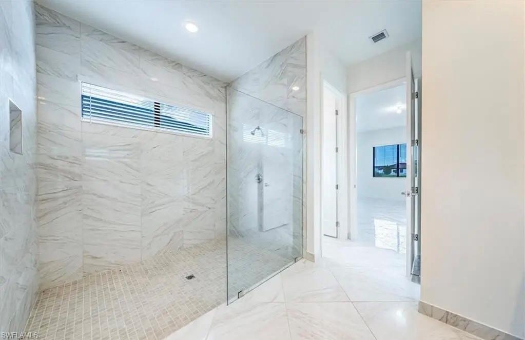 Bathroom featuring a marble finish shower and light marble finish floors