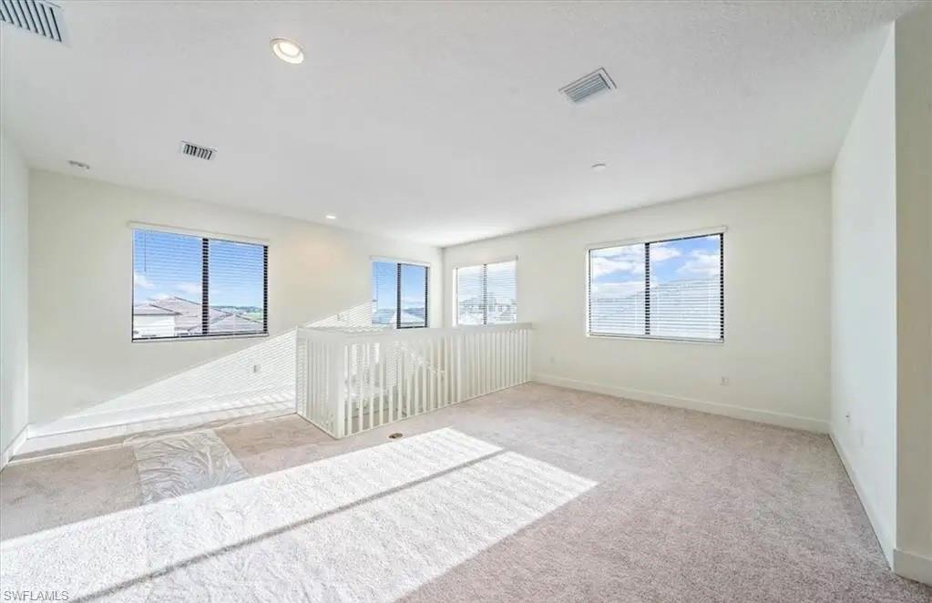 Empty room featuring light carpet, plenty of natural light, and recessed lighting