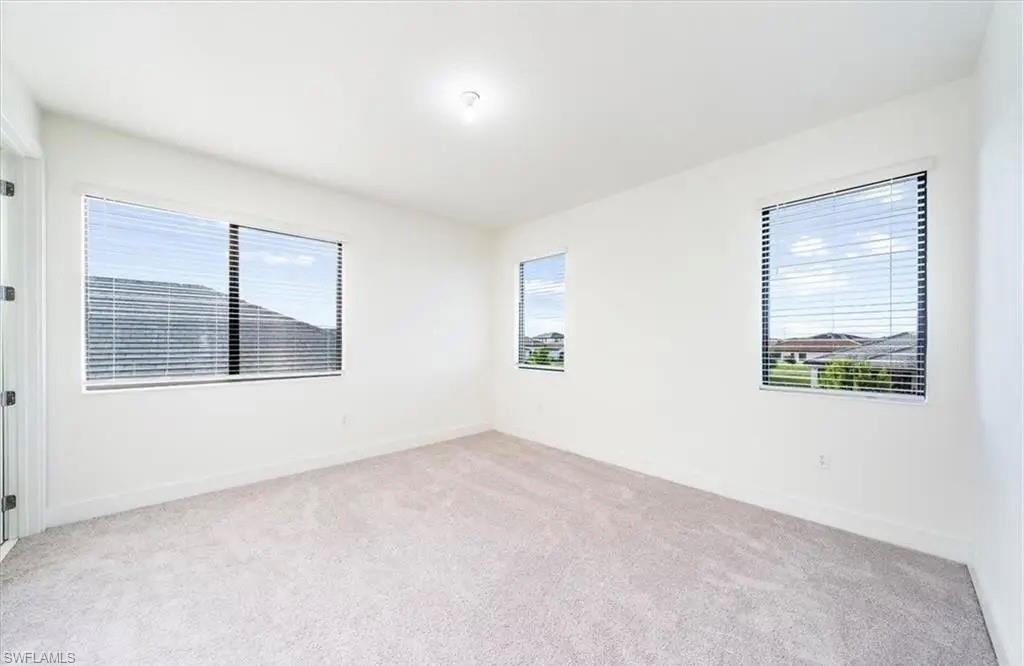 Empty room featuring light colored carpet and baseboards