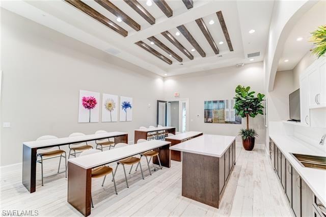 Kitchen featuring a kitchen island, recessed lighting, beamed ceiling, and white cabinets