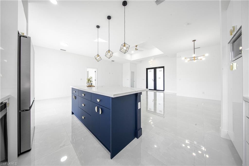 Kitchen featuring white cabinetry, french doors, pendant lighting, and open floor plan