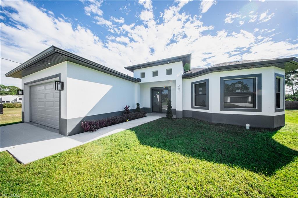 Rear view of property featuring stucco siding, a garage, and a lawn