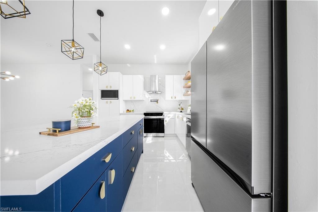 Kitchen featuring white cabinetry,appliances with stainless steel finishes, pendant lighting, open shelves, and blue cabinets