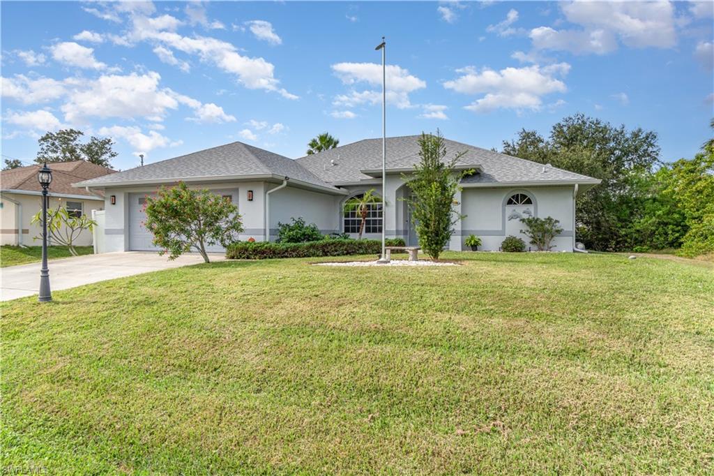 Ranch-style house featuring stucco siding, a front lawn, concrete driveway, a garage, and roof with shingles
