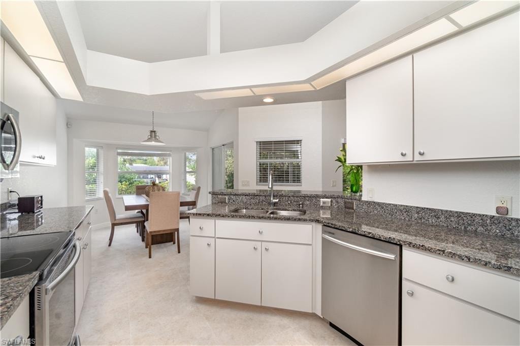 Kitchen with stainless steel appliances, dark stone counters
