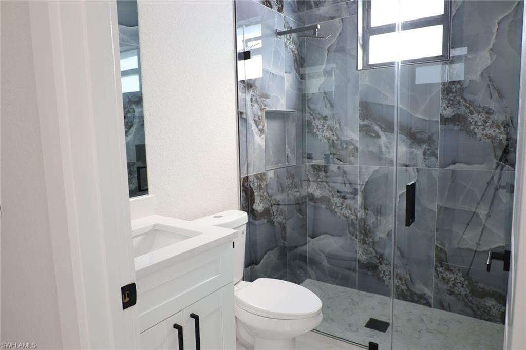 Full bath with a marble finish shower, vanity, and a textured wall