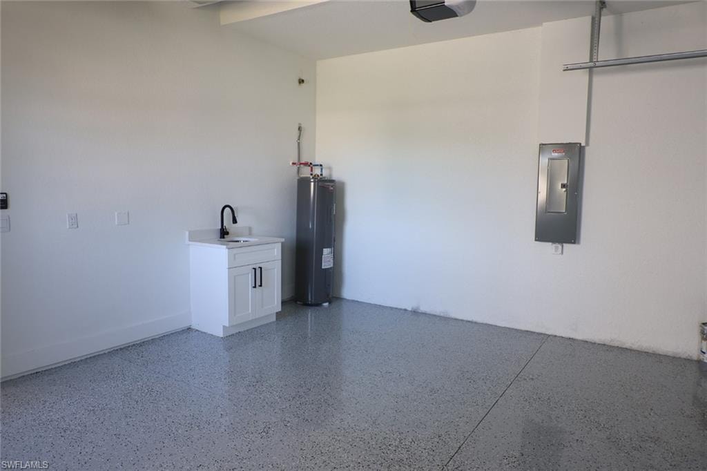 Garage with electric panel, electric water heater, and a garage door opener