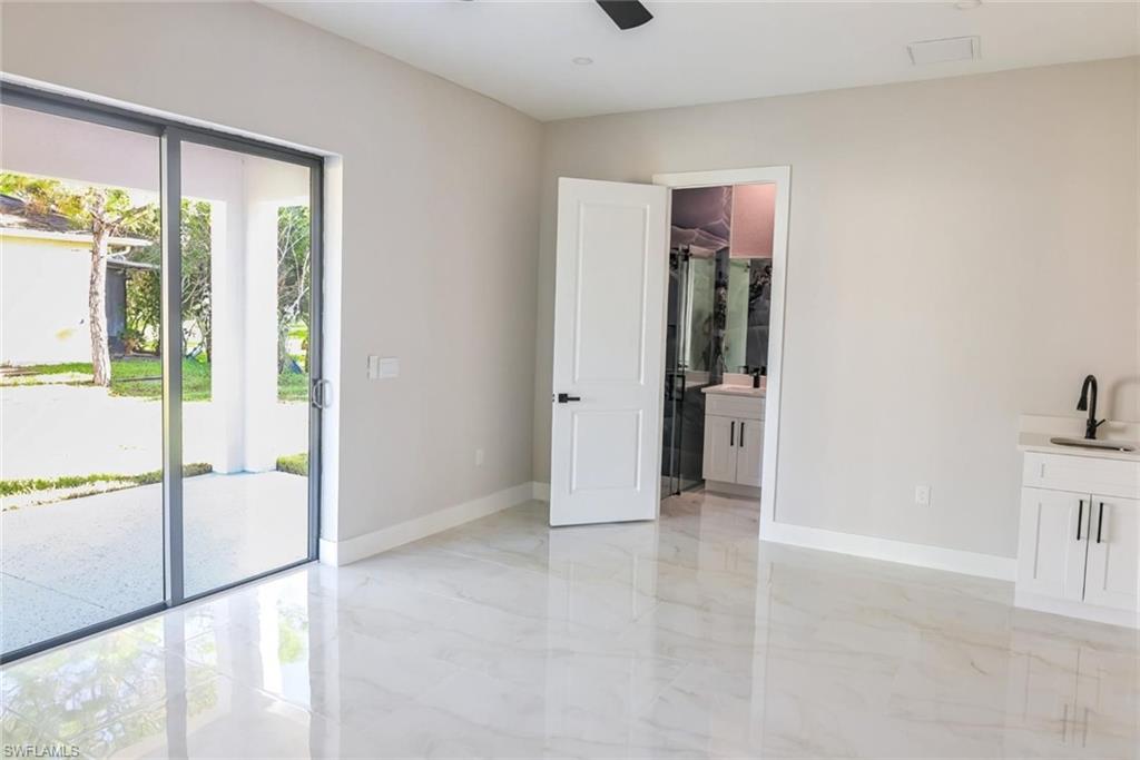 Unfurnished bedroom featuring connected bathroom, access to outside, ceiling fan, and light marble finish flooring
