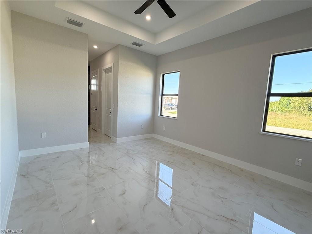 Empty room featuring light marble finish floors, a raised ceiling, recessed lighting, and ceiling fan