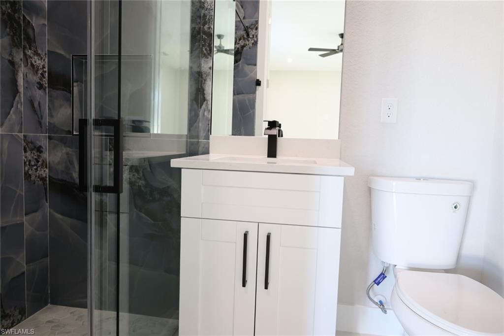 Bathroom with a marble finish shower, vanity, and a ceiling fan