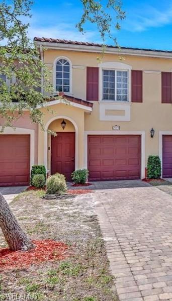 Mediterranean / spanish house featuring decorative driveway, an attached garage, and stucco siding