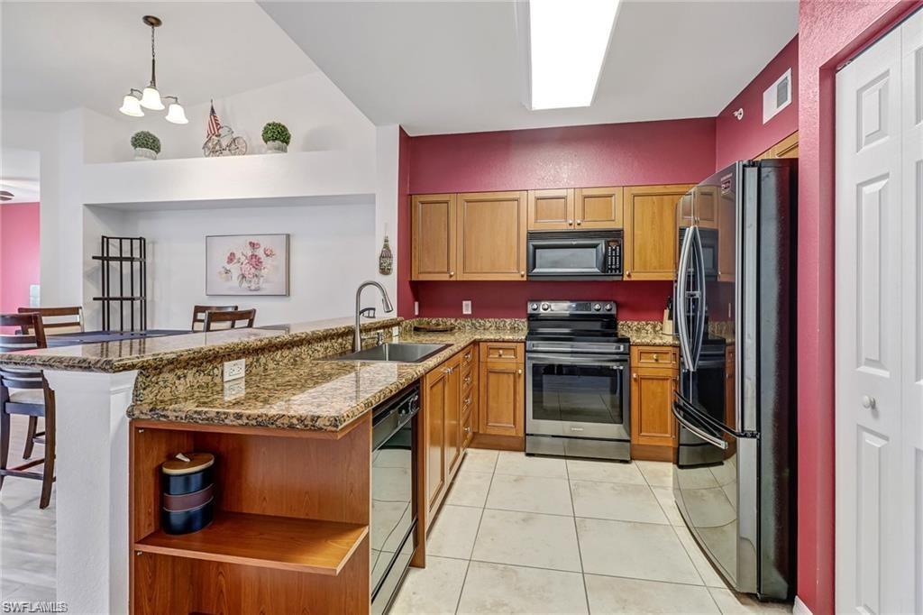 Kitchen with open shelves, black appliances, a kitchen breakfast bar, dark stone counters, and a peninsula