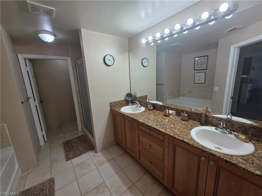 Full bathroom with a garden tub, double vanity, light tile patterned floors, and a shower stall