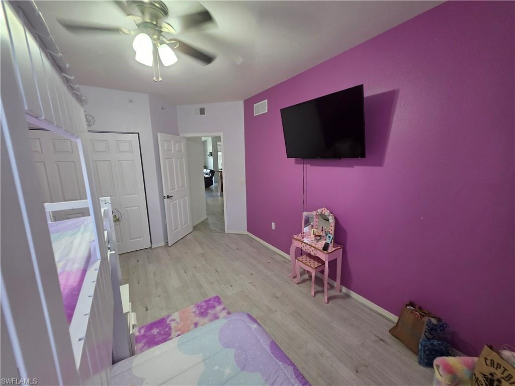 Bedroom with light wood-type flooring, a ceiling fan, and a closet