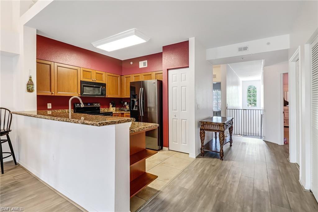 Kitchen with black appliances, dark stone countertops, light wood finished floors, a peninsula, and open shelves