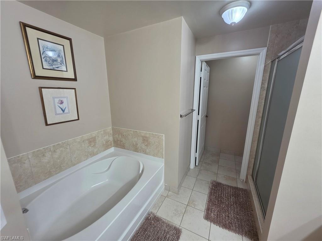 Full bathroom featuring a garden tub, light tile patterned floors, and a stall shower