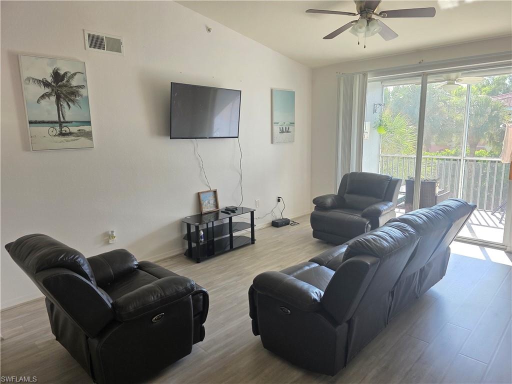 Living room with wood finished floors, a ceiling fan, and vaulted ceiling