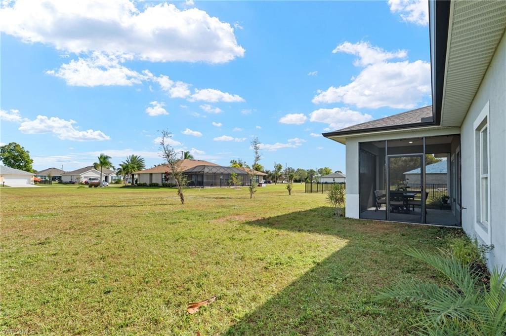 View of grassy yard featuring a sunroom and a residential view
