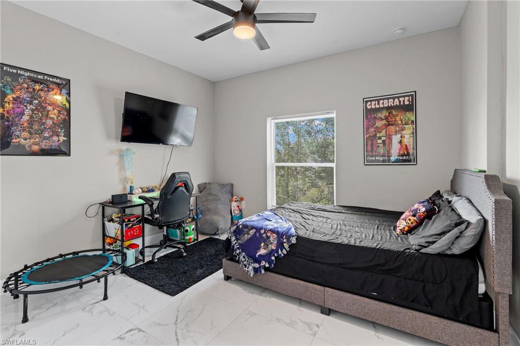 Bedroom featuring marble look tile flooring and ceiling fan