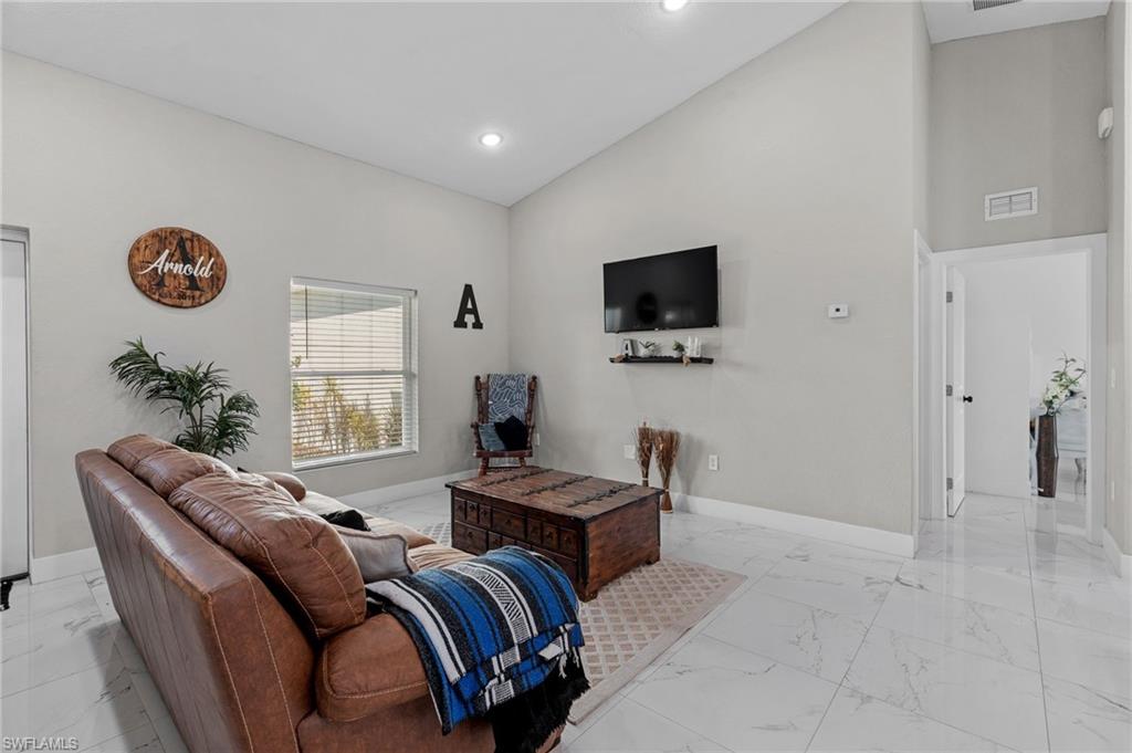 Living room featuring high vaulted ceiling, light marble finish floors, and recessed lighting