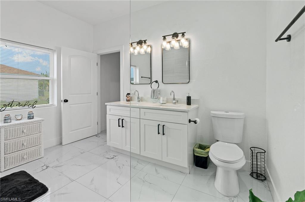 Bathroom featuring double vanity and light marble finish floors