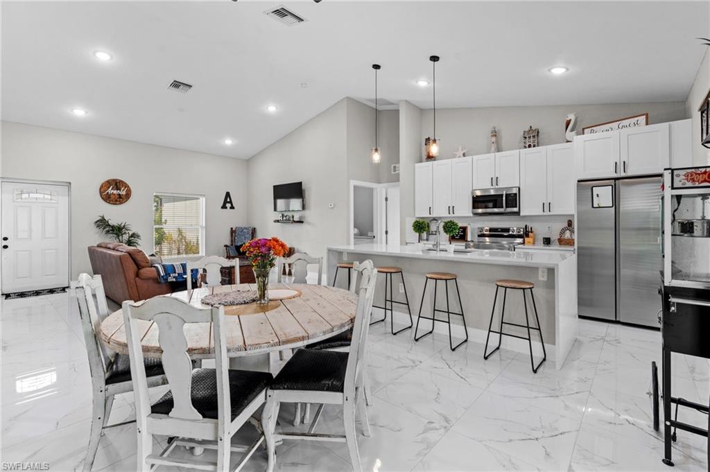 Dining room featuring light marble finish flooring, recessed lighting, and high vaulted ceiling
