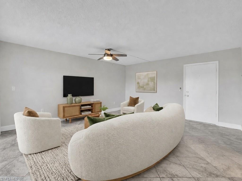 Virtual Staged Spacious living area featuring light gray walls, large format tile flooring, and a ceiling fan with integrated lighting