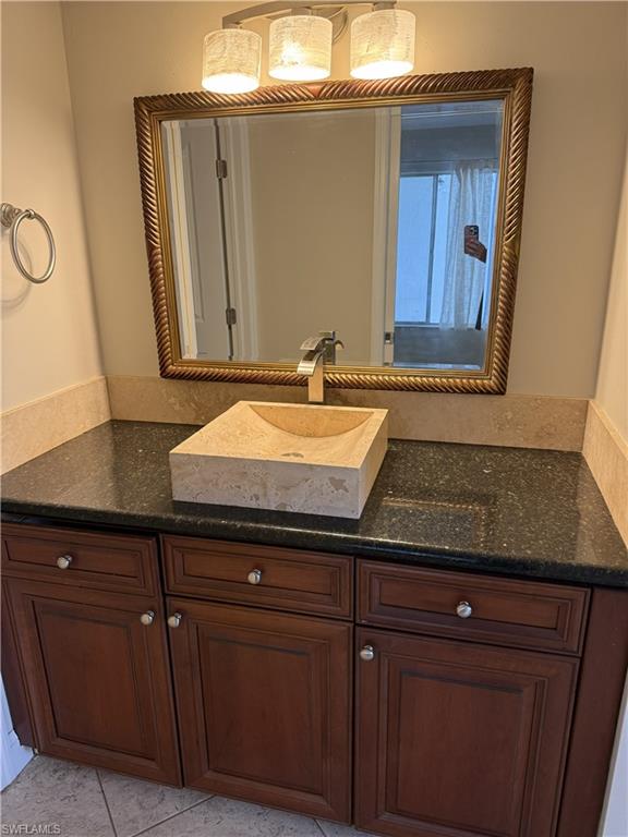 Dark wood-finish vanity with a stone countertop, featuring a vessel sink and a framed mirror
