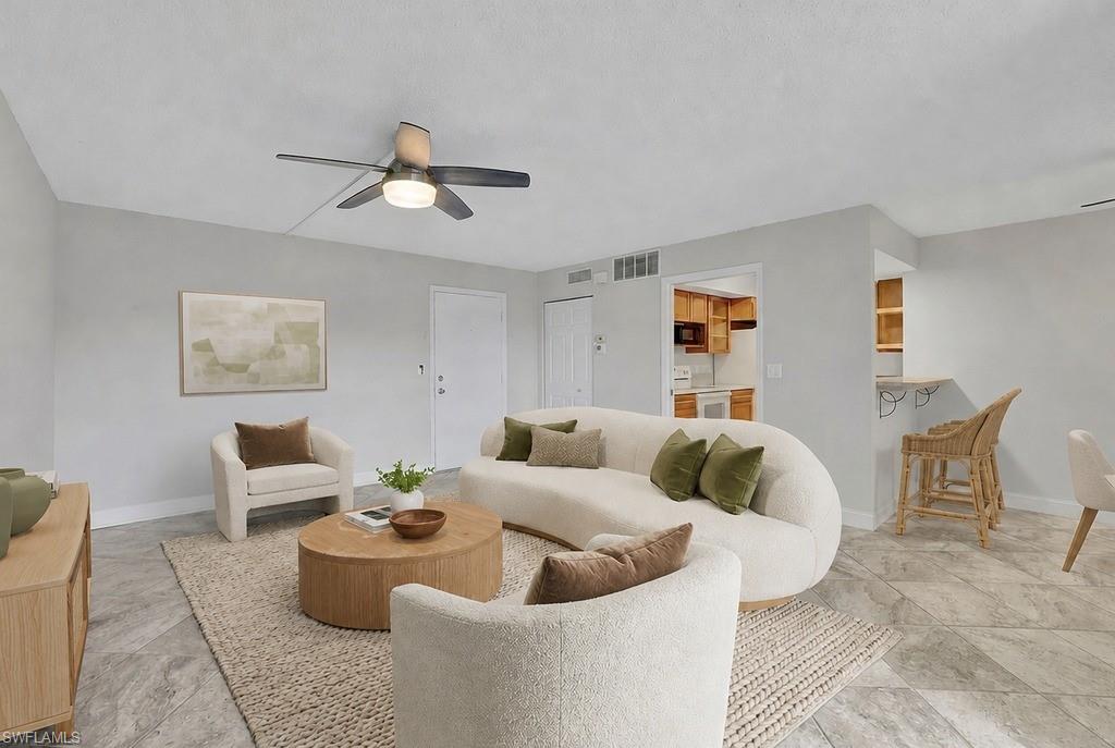 Virtual staged Spacious living area featuring light gray walls, a ceiling fan with integrated lighting, and durable tile flooring