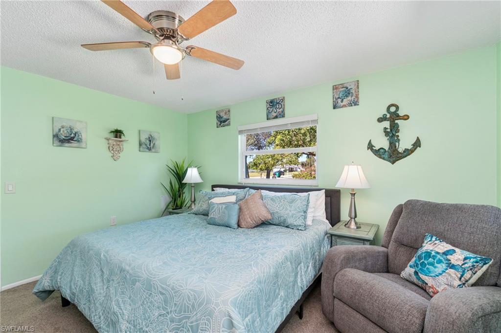 Carpeted bedroom featuring a textured ceiling and a ceiling fan