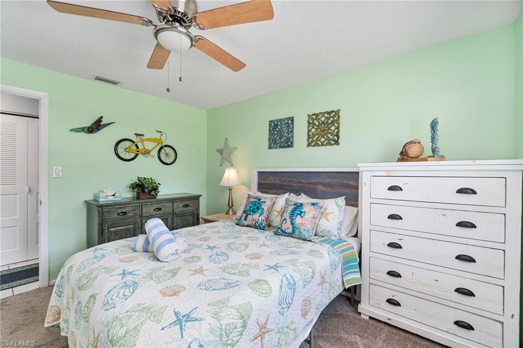 Bedroom with carpet, a ceiling fan, and a textured ceiling