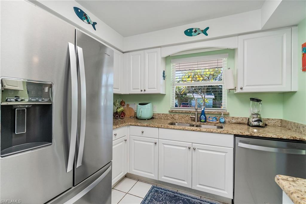 Kitchen featuring stainless steel appliances, white cabinetry, and light stone counters