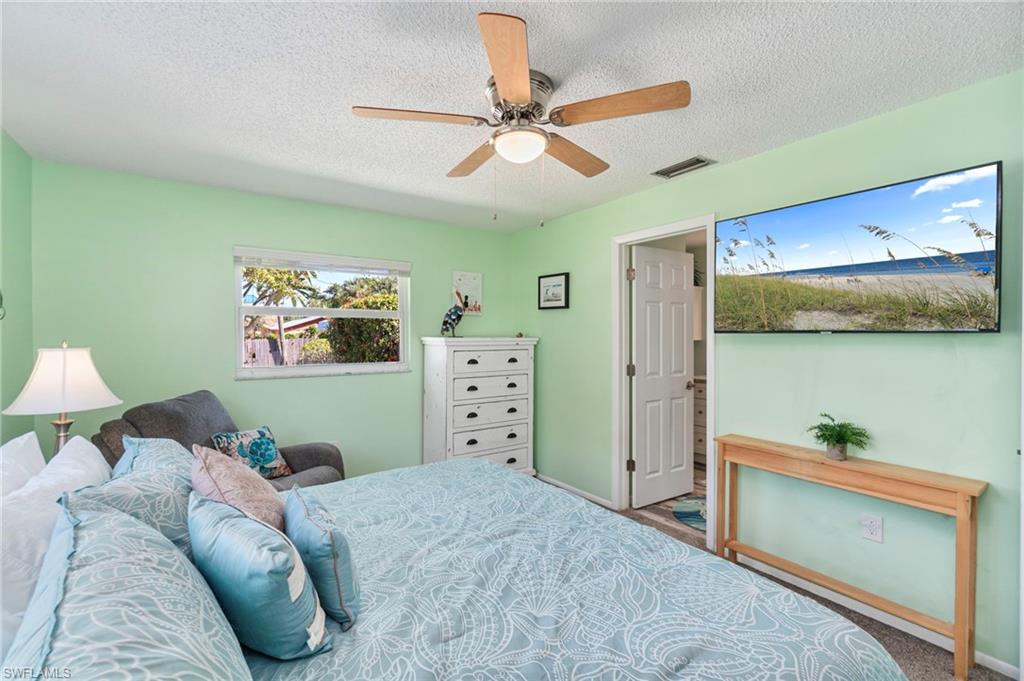 Bedroom with a textured ceiling, ceiling fan, and carpet
