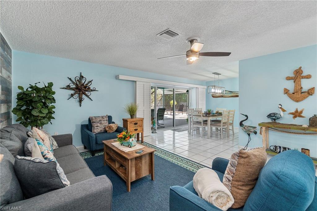 Living room with a textured ceiling, tile patterned flooring, and a ceiling fan
